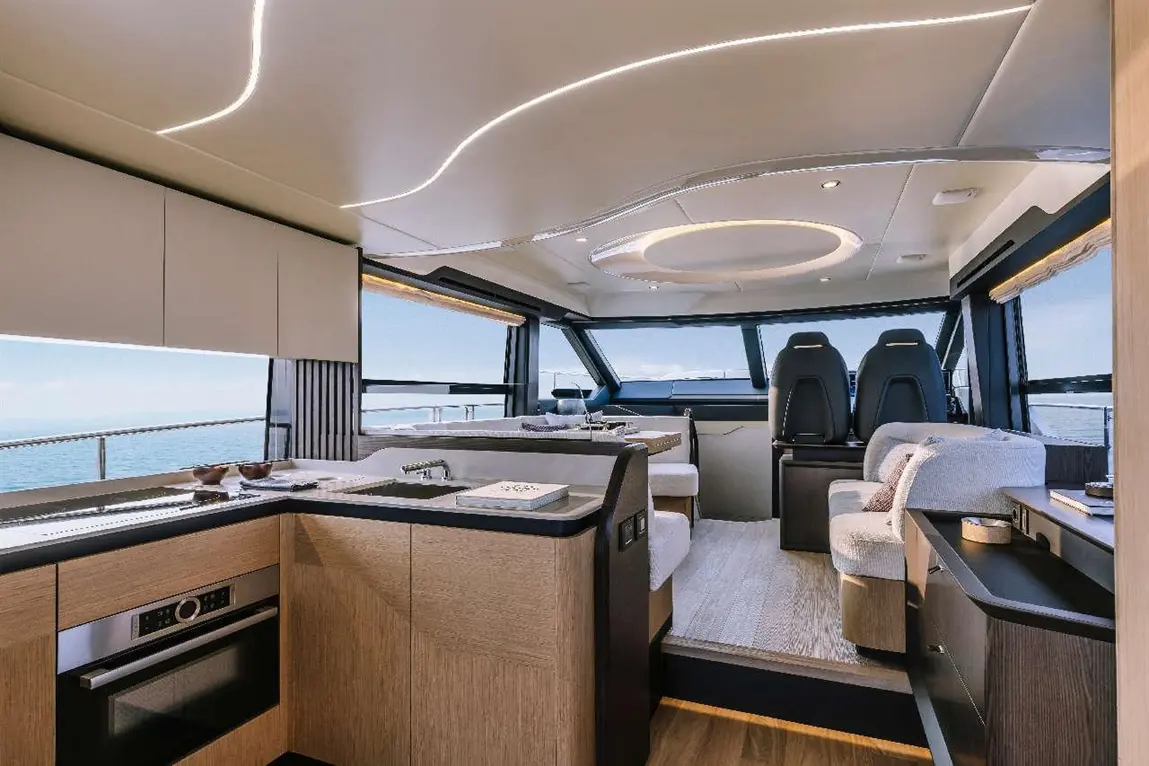 Luxurious yacht interior with modern kitchen, plush seating, and panoramic sea views through large windows.
